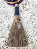 Blue Evil Eye Fatima Hand Broom - Protection and Good Fortune  Handheld broom of stiff grass, bound with blue cord and decorated with a blue Evil Eye and Fatima Hand charms.