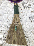 Green Adventurine Triquetra Broom - Luck and Prosperity  Handheld broom of stiff grass, bound with green cord and decorated with a silver Triquetra symbol charm with Green Aventurine crystals.